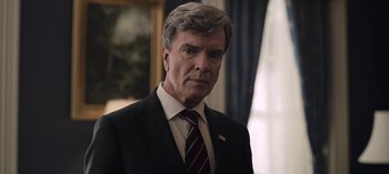 Movie still from “The Night Agent” (2023), created by Shawn Ryan – A person wearing a suit and tie; Close Up shot, Over the shoulder angle