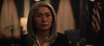 Movie still from “The Night Agent” (2023), created by Shawn Ryan – A woman wearing glasses and a jacket; Close Up shot, Over the shoulder angle
