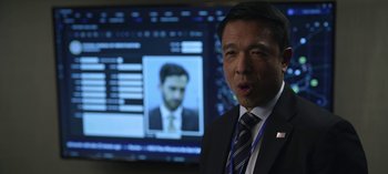 Movie still from “The Night Agent” (2023), created by Shawn Ryan – A man standing in front of a computer screen; Close Up shot, Over the shoulder angle