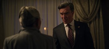 Movie still from “The Night Agent” (2023), created by Shawn Ryan – A man wearing a suit and tie talking to another man wearing a suit and tie; Close Up shot, Over the shoulder angle