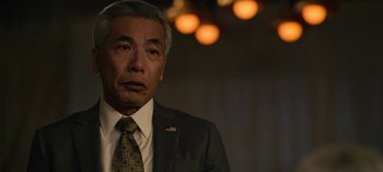 Movie still from “The Night Agent” (2023), created by Shawn Ryan – An older man in a suit and tie looking to his left; Close Up shot, Over the shoulder angle