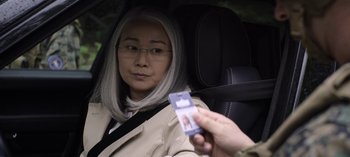 Movie still from “The Night Agent” (2023), created by Shawn Ryan – An older woman sitting in the back seat of a car; Close Up shot, Over the shoulder angle