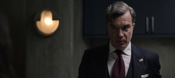 Movie still from “The Night Agent” (2023), created by Shawn Ryan – A person wearing a suit and tie; Close Up shot, Over the shoulder angle