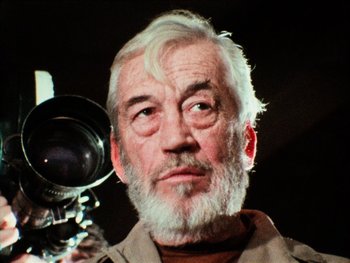 Movie still from “The Other Side of the Wind” (2018), directed by Orson Welles – An older man holding a camera up to his face; Close Up shot, Low angle