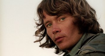 Movie still from “The Other Side of the Wind” (2018), directed by Orson Welles – A person with long hair and green eyes; Close Up shot, Low angle