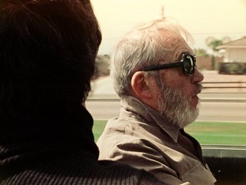 Movie still from “The Other Side of the Wind” (2018), directed by Orson Welles – An older man with a beard wearing sunglasses; Close Up shot, Over the shoulder angle