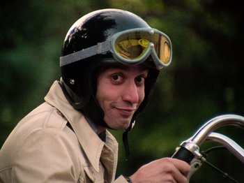 Movie still from “The Other Side of the Wind” (2018), directed by Orson Welles – A man wearing a motorcycle helmet and riding a motorcycle; Close Up shot, Low angle