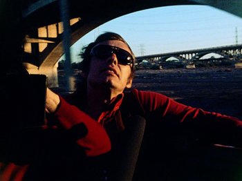 Movie still from “The Other Side of the Wind” (2018), directed by Orson Welles – A man in a red shirt is sitting in a car; Close Up shot, Low angle