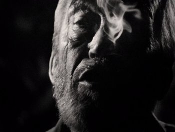 Movie still from “The Other Side of the Wind” (2018), directed by Orson Welles – An old man is smoking a cigarette in the dark; Extreme Close Up shot, Low angle