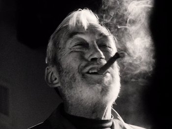 Movie still from “The Other Side of the Wind” (2018), directed by Orson Welles – An older man with a beard smoking a cigarette; Close Up shot, Low angle