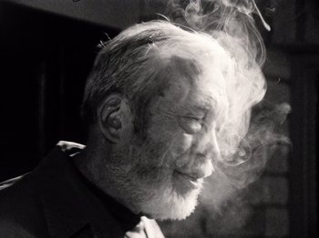 Movie still from “The Other Side of the Wind” (2018), directed by Orson Welles – An old man with a beard is smoking a cigarette; Close Up shot, Low angle