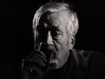 Movie still from “The Other Side of the Wind” (2018), directed by Orson Welles – An older man with a beard is smoking a cigarette; Close Up shot, Low angle