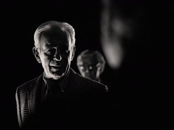 Movie still from “The Other Side of the Wind” (2018), directed by Orson Welles – A black and white photo of a man in a suit and tie; Medium shot, Low angle