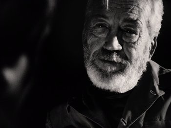 Movie still from “The Other Side of the Wind” (2018), directed by Orson Welles – An old man with a beard and a goatee looking at the camera; Close Up shot, Over the shoulder angle