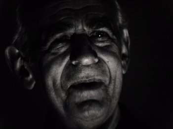 Movie still from “The Other Side of the Wind” (2018), directed by Orson Welles – An old man with a black shirt and a black background; Close Up shot, Low angle