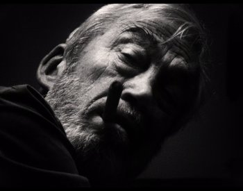 Movie still from “The Other Side of the Wind” (2018), directed by Orson Welles – An old man with a beard is smoking a cigarette; Extreme Close Up shot, Low angle