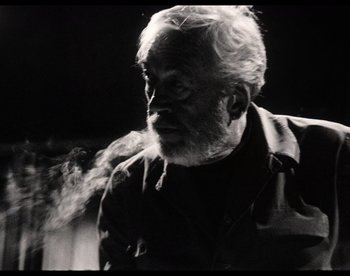 Movie still from “The Other Side of the Wind” (2018), directed by Orson Welles – An old man with a beard is smoking a cigarette; Close Up shot, Low angle