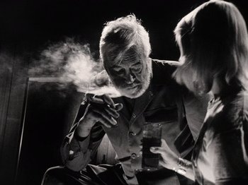 Movie still from “The Other Side of the Wind” (2018), directed by Orson Welles – An older man smoking a cigarette while holding a glass of wine; Close Up shot, Low angle