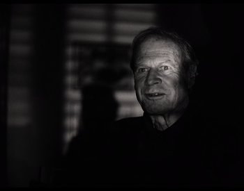 Movie still from “The Other Side of the Wind” (2018), directed by Orson Welles – An older man is smiling for the camera; Close Up shot, Over the shoulder angle