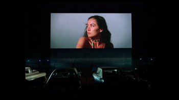 Movie still from “The Other Side of the Wind” (2018), directed by Orson Welles – A woman is sitting in front of a movie screen; Wide shot, Low angle