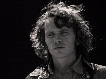 Movie still from “The Other Side of the Wind” (2018), directed by Orson Welles – A black and white photo of a man with long curly hair; Close Up shot, Low angle