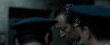 Movie still from “The Outsider” (2018), directed by Martin Zandvliet – A man with a hat looking down at another man with a hat; Close Up shot, Over the shoulder angle