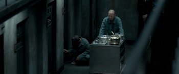 Movie still from “The Outsider” (2018), directed by Martin Zandvliet – Two men are sitting on the floor in front of a stove; Wide shot, High angle