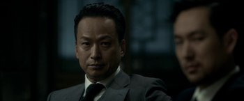 Movie still from “The Outsider” (2018), directed by Martin Zandvliet – A person wearing a suit and tie; Close Up shot, Low angle