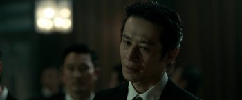 Movie still from “The Outsider” (2018), directed by Martin Zandvliet – A person wearing a suit and tie; Close Up shot, Over the shoulder angle