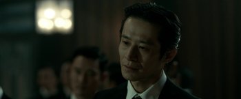 Movie still from “The Outsider” (2018), directed by Martin Zandvliet – A person wearing a suit and tie; Close Up shot, Over the shoulder angle