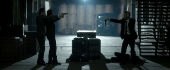 Movie still from “The Outsider” (2018), directed by Martin Zandvliet – Two men are holding guns in a dark room; Wide shot, High angle