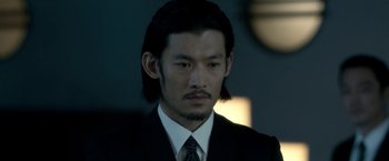 Movie still from “The Outsider” (2018), directed by Martin Zandvliet – A person wearing a suit and tie; Close Up shot, Low angle