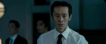 Movie still from “The Outsider” (2018), directed by Martin Zandvliet – A man in a white dress shirt and black tie; Close Up shot, Low angle