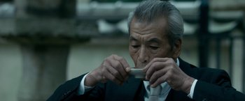 Movie still from “The Outsider” (2018), directed by Martin Zandvliet – An older man in a black suit and white tie eating; Close Up shot, Low angle