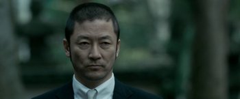 Movie still from “The Outsider” (2018), directed by Martin Zandvliet – A person wearing a suit and tie; Close Up shot, Low angle