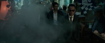 Movie still from “The Outsider” (2018), directed by Martin Zandvliet – A group of men in suits and ties walking through smoke; Medium shot, Low angle
