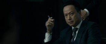 Movie still from “The Outsider” (2018), directed by Martin Zandvliet – A man in a suit holding a cigarette in his hand; Close Up shot, Low angle