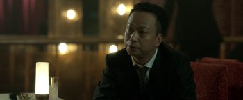 Movie still from “The Outsider” (2018), directed by Martin Zandvliet – A person wearing a suit and tie; Close Up shot, Low angle