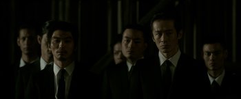 Movie still from “The Outsider” (2018), directed by Martin Zandvliet – A group of men standing next to each other in suits; Medium shot, Low angle