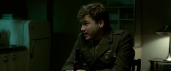 Movie still from “The Outsider” (2018), directed by Martin Zandvliet – A man sitting down with a beer in his mouth; Medium shot, Over the shoulder angle