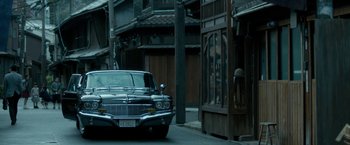 Movie still from “The Outsider” (2018), directed by Martin Zandvliet – An old car parked on the side of the street; Wide shot, Low angle