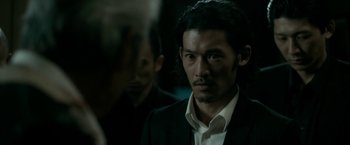 Movie still from “The Outsider” (2018), directed by Martin Zandvliet – A person wearing a suit and tie; Close Up shot, Over the shoulder angle