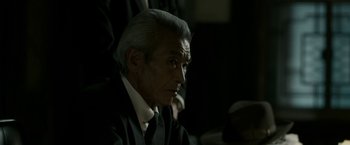 Movie still from “The Outsider” (2018), directed by Martin Zandvliet – An older man in a black suit and white shirt; Close Up shot, Over the shoulder angle