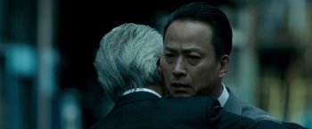 Movie still from “The Outsider” (2018), directed by Martin Zandvliet – A man in a black suit and a man in a white suit; Close Up shot, Over the shoulder angle