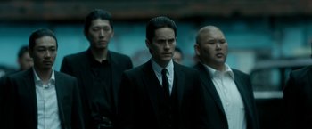 Movie still from “The Outsider” (2018), directed by Martin Zandvliet – A group of men standing next to each other in suits; Medium shot, Over the shoulder angle