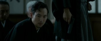 Movie still from “The Outsider” (2018), directed by Martin Zandvliet – A man wearing a black robe looking down at a woman; Close Up shot, Over the shoulder angle