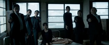 Movie still from “The Outsider” (2018), directed by Martin Zandvliet – A group of people standing around a bed; Wide shot, Low angle