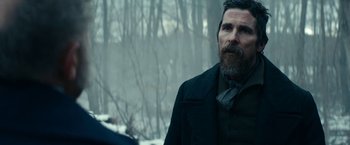 Movie still from “The Pale Blue Eye” (2022), directed by Scott Cooper – A man with a long beard standing next to a forest; Close Up shot, Over the shoulder angle