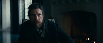 Movie still from “The Pale Blue Eye” (2022), directed by Scott Cooper – A person wearing a suit and tie; Medium shot, Over the shoulder angle