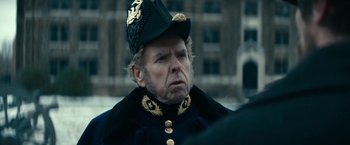 Movie still from “The Pale Blue Eye” (2022), directed by Scott Cooper – An old man wearing a hat and a uniform; Close Up shot, Over the shoulder angle